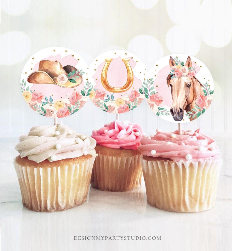 May include: Three cupcake toppers with a pink background and floral accents. The toppers feature a cowboy hat, a horseshoe, and a horse's head with a floral crown.