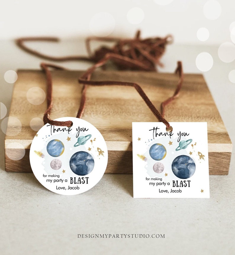 May include: Two round and square thank you tags with a space theme. The tags feature planets, stars, and rockets. The text on the tags reads "Thank you for making my party a BLAST Love, Jacob".