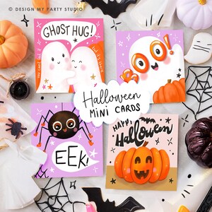 May include: A collection of Halloween mini cards with various designs. One card features two ghosts hugging with the text "Ghost Hug!". Another shows a spider with the word "EEK!". A third card has a pumpkin with the words "Happy Halloween". The cards are surrounded by Halloween decorations.