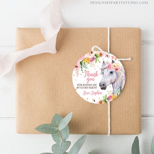 Puede incluir: Un regalo envuelto en papel marr&oacute;n con una etiqueta decorativa. La etiqueta presenta un caballo blanco con una corona floral y el texto "Thank you for riding on by to my party! Love, Sophia."