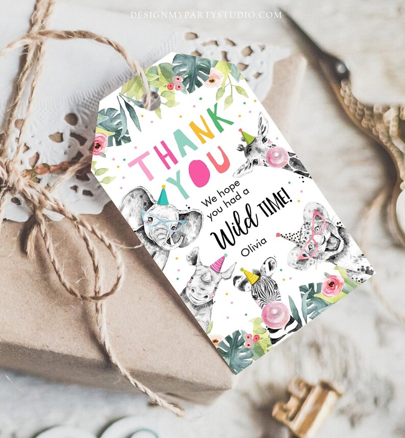 May include: A white thank you tag with colorful text that says "Thank You" and "We hope you had a Wild Time!" with a giraffe, elephant, rhino, zebra, and lion wearing party hats. The tag is decorated with green leaves, pink flowers, and colorful confetti.