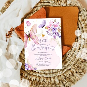 K&ouml;nnte beinhalten: Eine Babyparty-Einladung mit einem rosa und violetten Schmetterlingsdesign. Der Text lautet "a little butterfly is on the way".