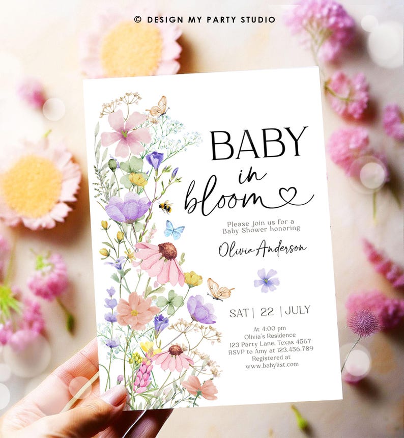 May include: A baby shower invitation with a floral design. The invitation says "Baby in Bloom" and features a watercolor illustration of pink, purple, and yellow flowers. The text also includes the date, time, and location of the shower, as well as the name of the guest of honor, Olivia Anderson.