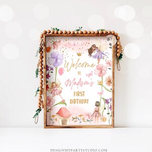 May include: A pink and purple fairy-themed welcome sign with gold lettering that reads "Welcome to Madison's First Birthday". The sign features illustrations of fairies, flowers, butterflies, and a mushroom house.