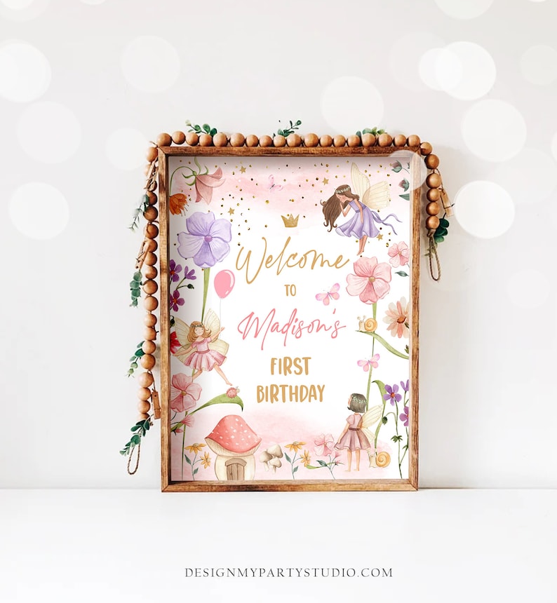 May include: A pink and purple fairy-themed welcome sign with gold lettering that reads "Welcome to Madison's First Birthday". The sign features illustrations of fairies, flowers, butterflies, and a mushroom house.