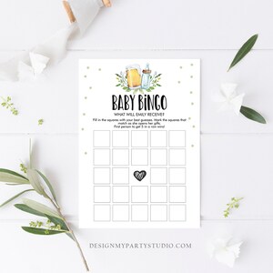 May include: A printable baby bingo card with a green and white polka dot background. The card has a title that says "Baby Bingo" and the text "What will Emily receive?" The card has 25 squares with a black and white striped heart in the center square.