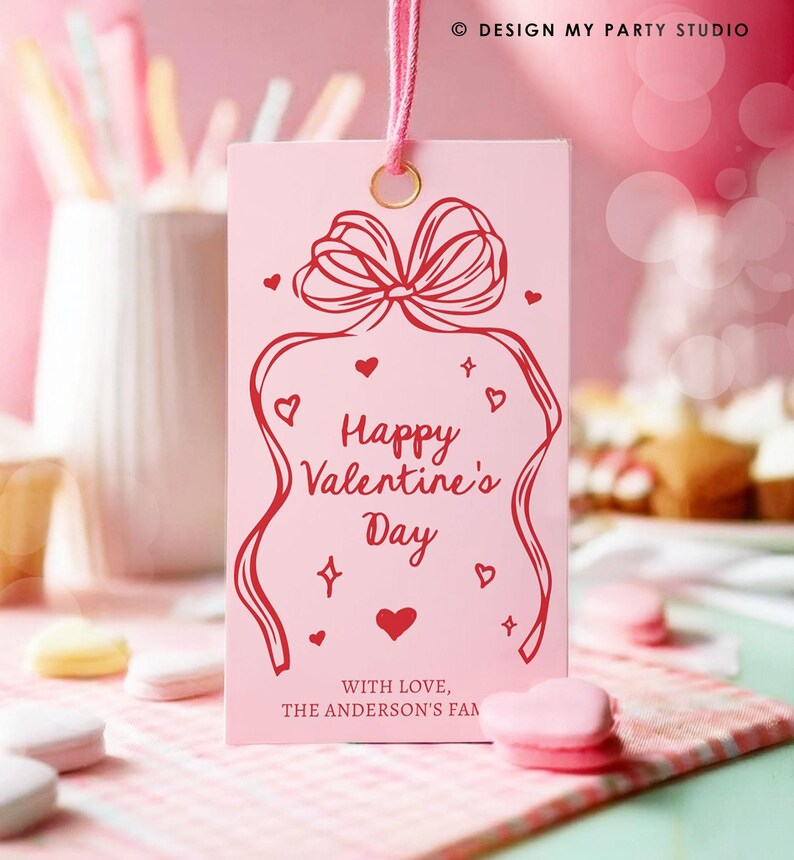 Puede incluir: Etiqueta de regalo rosa con un lazo rojo y el texto "Feliz d&iacute;a de San Valent&iacute;n" y "Con amor, La familia Anderson".