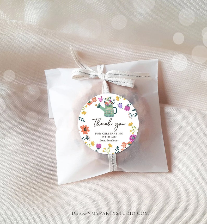 May include: A round thank you favor tag with a colorful floral design and a green watering can. The tag says "Thank you for celebrating with me! Love, Penelope".