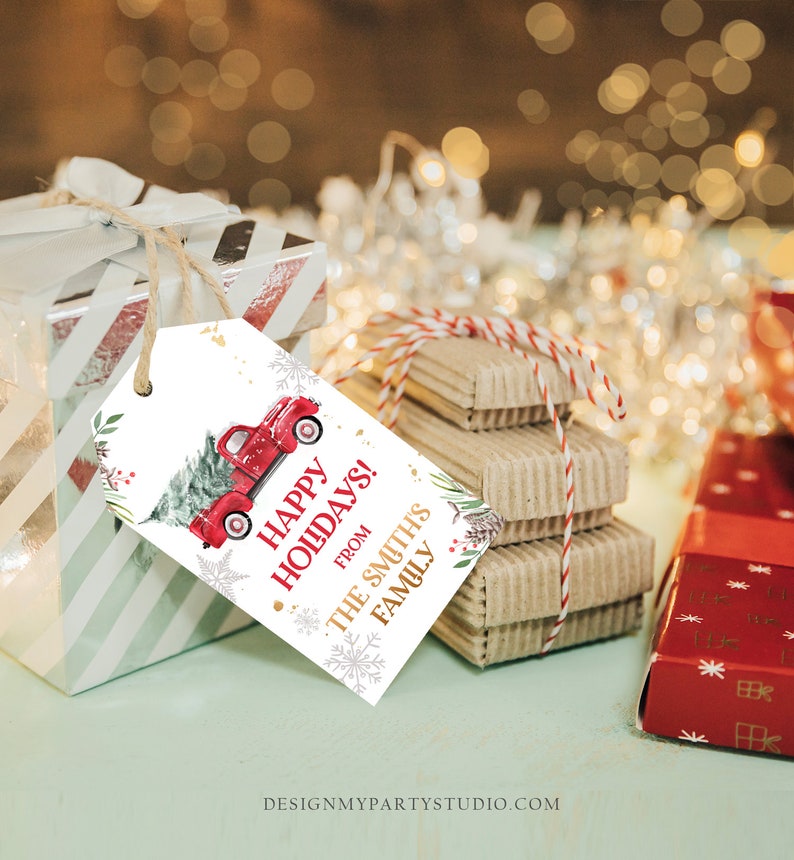Puede incluir: Una etiqueta de regalo navide&ntilde;a con un cami&oacute;n rojo vintage que lleva un &aacute;rbol de Navidad, con las palabras "Happy Holidays!" y "From The Smith's Family". La etiqueta est&aacute; atada a un regalo envuelto con hilo.