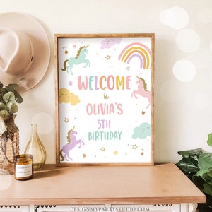 K&ouml;nnte beinhalten: Ein Willkommens-Schild f&uuml;r eine 5. Geburtstagsfeier mit einem Einhorn-Thema. Das Schild zeigt einen Regenbogen, Wolken, Sterne und Einh&ouml;rner in den Farben Pink, Blau und Gelb. Der Text auf dem Schild lautet "Willkommen zu Olivia's 5th Birthday".