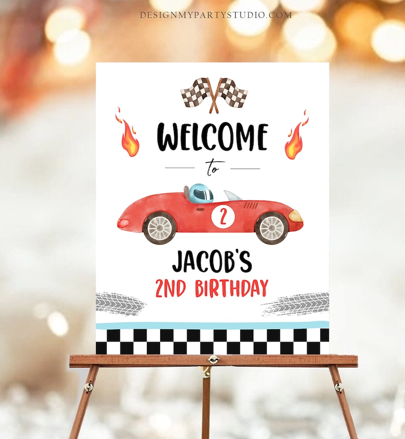 May include: Welcome to Jacob's 2nd Birthday party sign with a red race car, checkered flags, and flames.