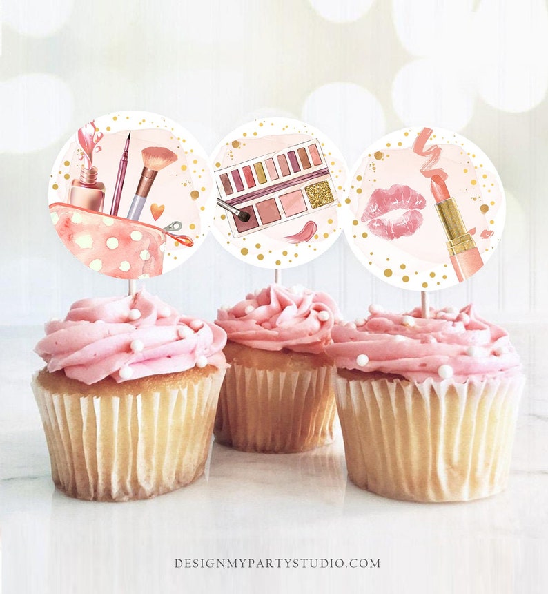 May include: Three round cupcake toppers with images of makeup items. The first topper features a pink makeup bag with lipstick, eyeliner, and a makeup brush. The second topper shows a pink eyeshadow palette with gold glitter. The third topper has a pink lipstick and a gold lipstick tube.