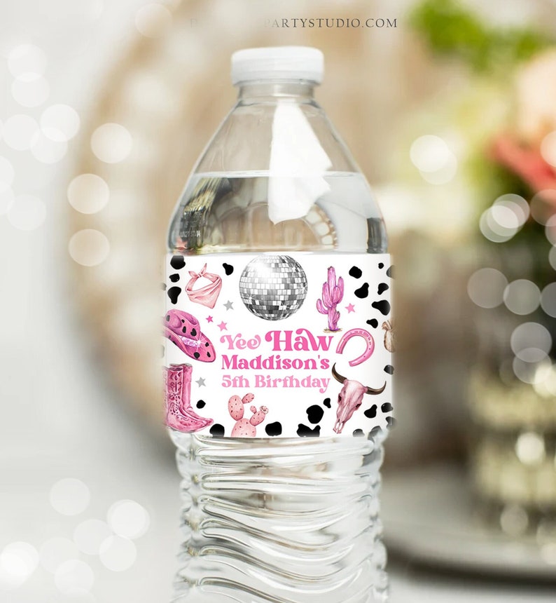 May include: Water bottle label with a pink and white cow print background. The label features a pink cowboy hat, boots, a disco ball, a cactus, and a horseshoe. The text on the label reads "Yee Haw Maddison's 5th Birthday".