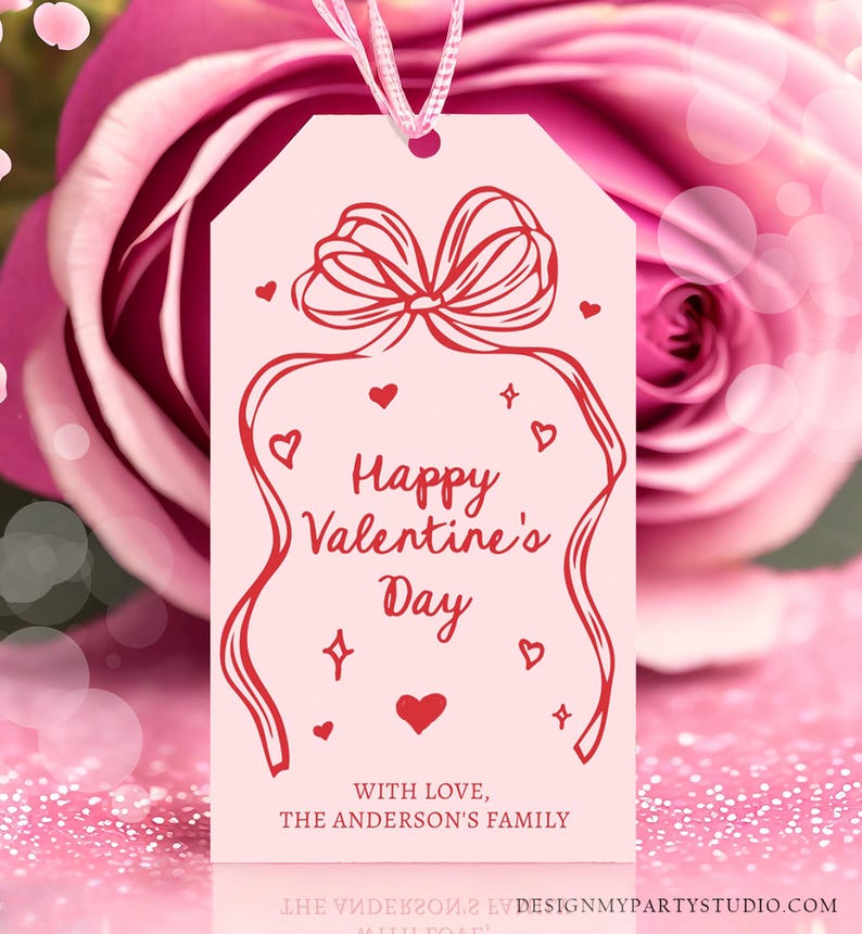 Puede incluir: Etiqueta de regalo rosa con un lazo rojo y un dise&ntilde;o de lazo. El texto dice "Feliz d&iacute;a de San Valent&iacute;n" con un coraz&oacute;n rojo y las palabras "Con amor, La familia Anderson".