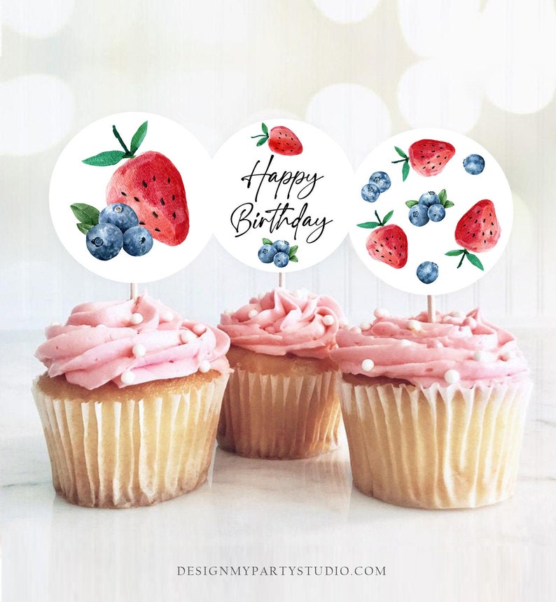 May include: Three cupcakes with pink frosting and white sprinkles topped with round cupcake toppers. The toppers feature watercolor illustrations of strawberries and blueberries. One topper says "Happy Birthday".