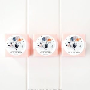 Puede incluir: Tres cajas de regalo rosas con etiquetas redondas blancas. Las etiquetas muestran un astronauta de dibujos animados sosteniendo globos con planetas y estrellas. El texto en las etiquetas dice "Gracias" y "Por hacer que mi cumplea&ntilde;os sea fuera de este mundo! Con cari&ntilde;o, Mason".