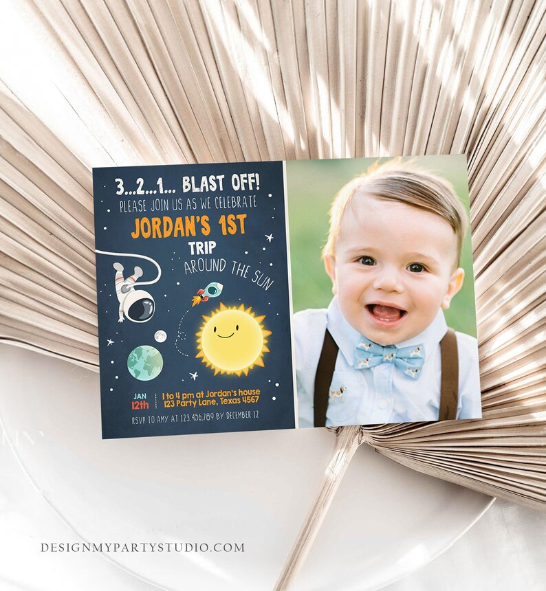 May include: A blue and orange space-themed birthday invitation for a boy's first birthday party. The invitation features an astronaut, a rocket, a planet, and a sun. The text on the invitation reads "3...2...1... BLAST OFF! Please join us as we celebrate Jordan's 1st Trip Around the Sun. Jan 12th 1 to 4 pm at Jordan's house 123 Party Lane, Texas 4567 RSVP to Amy at 123.456.109 by December 12. DesignMyPartyStudio.com".