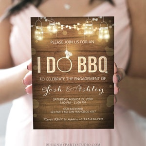 May include: A rustic wood-grain background with a white text overlay. The text reads "Please join us for an I DO BBQ to celebrate the engagement of Josh & Ashley. Saturday, August 27, 20XX 5:00 PM - 11:00 PM Our Backyard 123 Party Rd, San Francisco 4567 Please RSVP to Ashley at 123.456.789". The background features a string of lights with mason jars and a diamond ring.