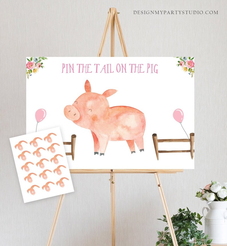 May include: A pink pig with a watercolor design stands in front of a wooden fence. The pig is looking to the left. There are two pink balloons in the background. The text "Pin the Tail on the Pig" is written in pink letters at the top of the image. There are 12 pink pig tails on a separate sheet of paper.