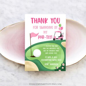 May include: A pink and green golf-themed thank you card with the text "Thank You For Swinging By My Par-Tee!". The card features a golf cart, golf ball, flag, and balloons. The card is on a pink plate.
