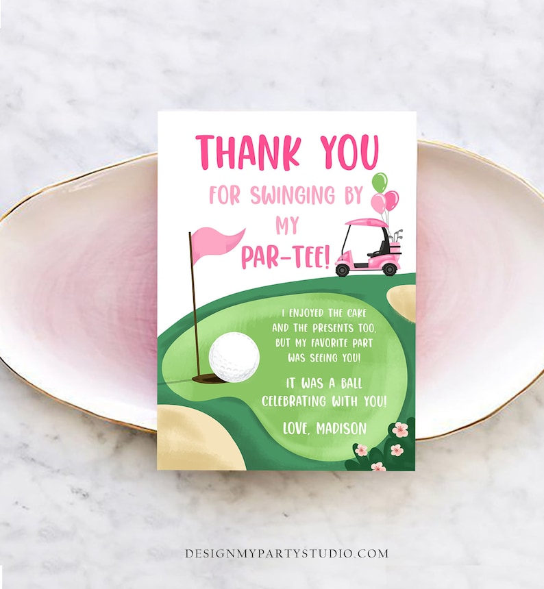 May include: A pink and green golf-themed thank you card with the text "Thank You For Swinging By My Par-Tee!". The card features a golf cart, golf ball, flag, and balloons. The card is on a pink plate.