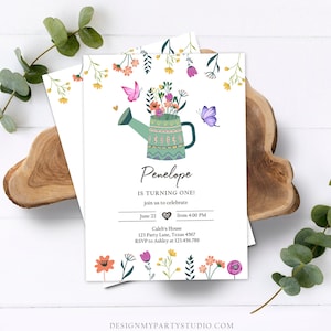 May include: A green watering can with a colorful floral arrangement and butterflies. The text "Penelope is turning one!" is written on the card. The card also includes the date, time, and location of the event.
