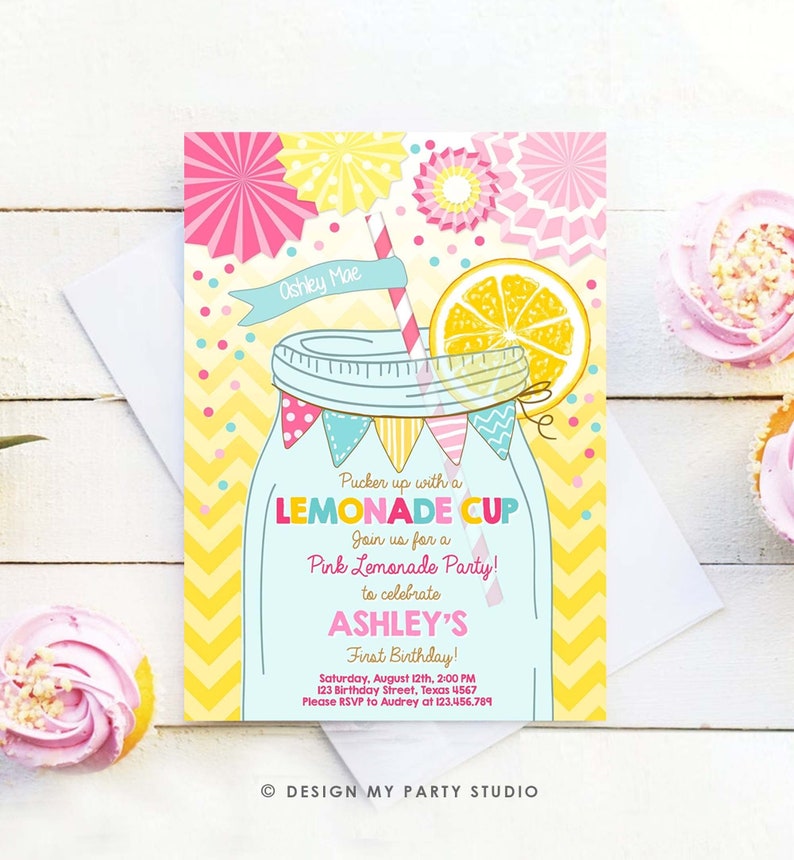 May include: A yellow and pink lemonade party invitation with a mason jar filled with lemonade and a lemon slice on top. The text reads "Pucker up with a LEMONADE CUP Join us for a Pink Lemonade Party! to celebrate ASHLEY'S First Birthday! Saturday, August 12th, 2:00 PM 123 Birthday Street, Texas 4567 Please RSVP to Audrey at 123,456,789 DESIGN MY PARTY STUDIO"