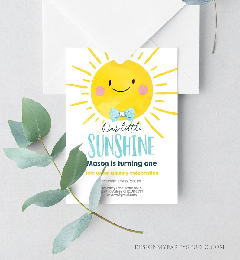 May include: A birthday invitation featuring a smiling yellow sun with a blue bow tie. The text reads "Our little SUNSHINE" and "Mason is turning one." Includes event details and a website address. A white envelope and greenery are in the background.