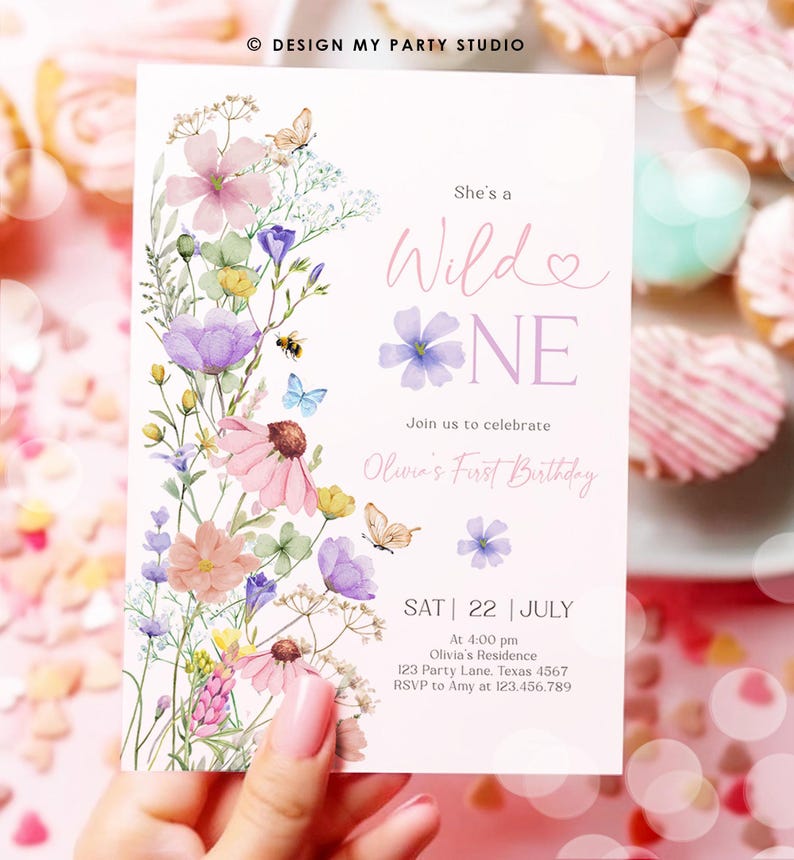 May include: A floral-themed first birthday invitation with a watercolor design featuring pink, purple, and yellow flowers, butterflies, and a bee. The text reads "She's a Wild One" and includes details for the party, including the date, time, location, and RSVP information.