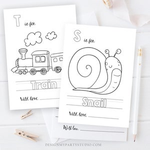 Op de afbeelding: Zwart-witte printbare alfabetkaarten met een trein en een slak. De kaarten bevatten de letters T en S en de woorden "Trein" en "Slak". De tekst "T is voor" en "S is voor" is ook op de kaarten te vinden. De kaarten hebben een ruimte om "Met liefde." te schrijven.