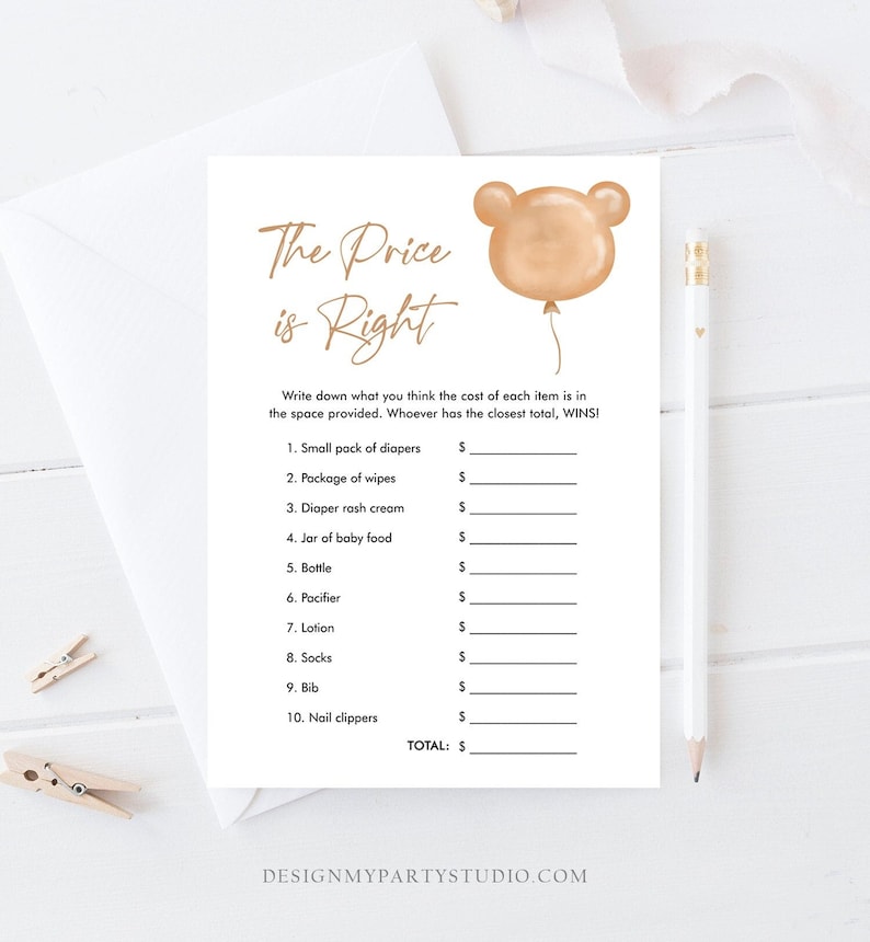 May include: A white baby shower game card with the text "The Price is Right" in gold script. The card features a bear-shaped balloon graphic and a list of baby items to price. A pencil and decorative clips are also visible.