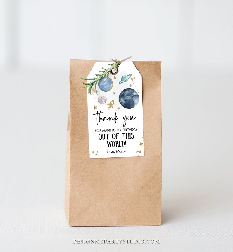May include: A brown paper bag with a thank you tag attached. The tag has a blue and white watercolor illustration of planets and a rocket ship. The text on the tag reads "Thank you for making my birthday out of this world! Love, Mason".