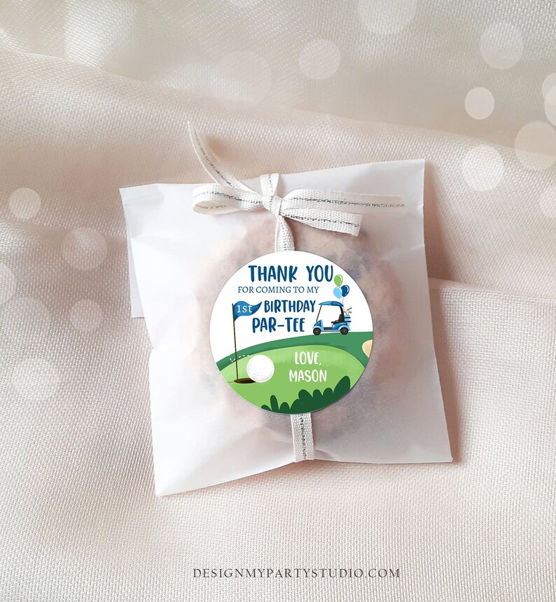 Peut inclure: Un autocollant rond vert et bleu avec une voiturette de golf, une balle de golf et un drapeau. L'autocollant dit "Merci d'&ecirc;tre venu &agrave; mon 1er anniversaire Par-Tee. Avec amour, Mason".
