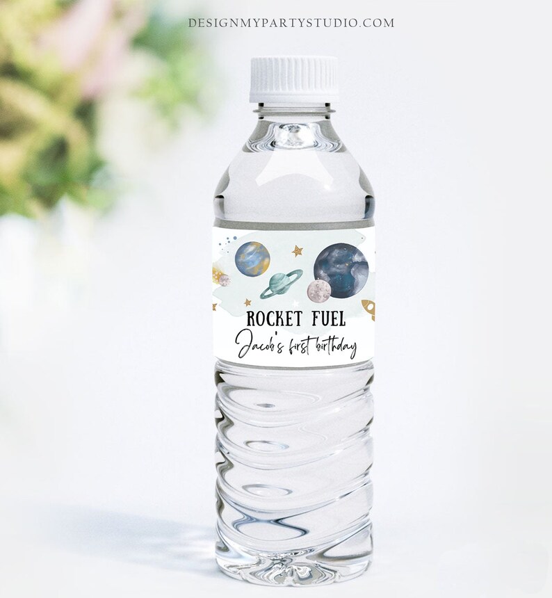 May include: Water bottle label with a space theme. The label features planets, stars, and a rocket ship. The text on the label reads "Rocket Fuel Jacob's first birthday".