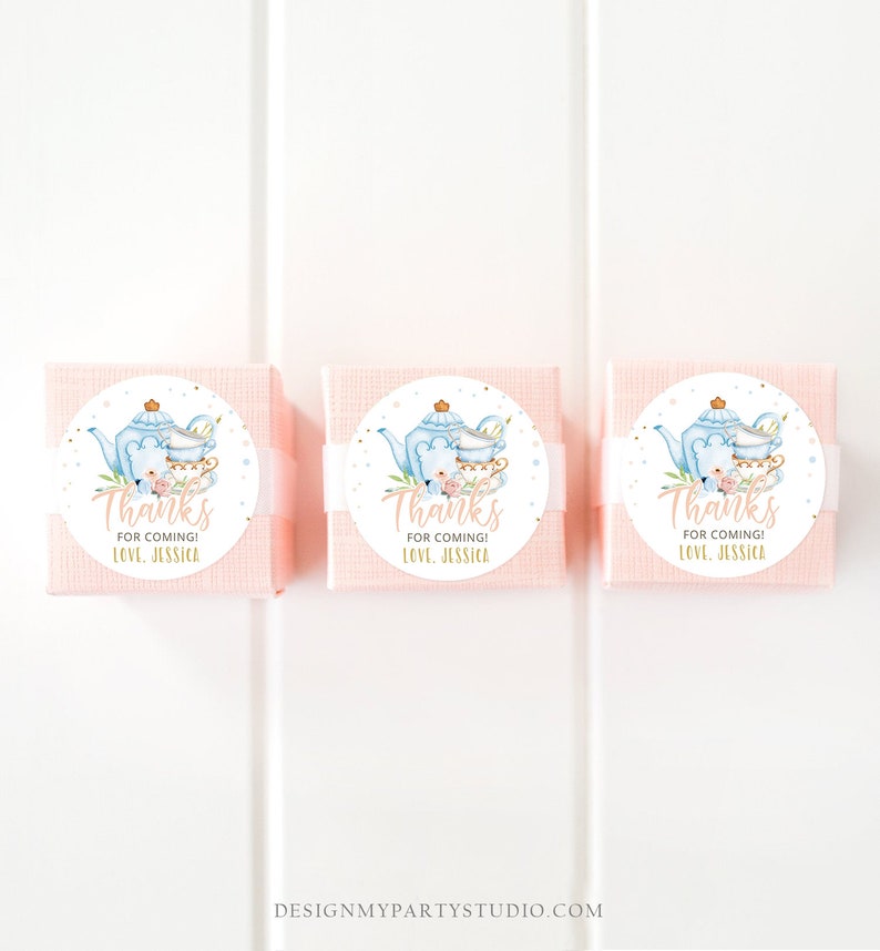 May include: Three pink favour boxes with white ribbon and round stickers. The stickers feature a blue teapot, teacups, and a bear with pink flowers. The text on the stickers reads "Thanks for coming! Love, Jessica."