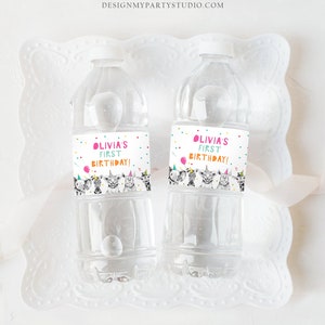 May include: Two clear plastic water bottles with colorful labels that say "Olivia's First Birthday!" and feature a cartoon illustration of animals wearing party hats.