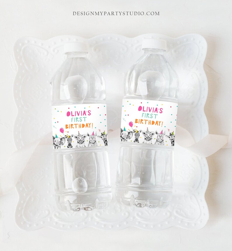 May include: Two clear plastic water bottles with colorful labels that say "Olivia's First Birthday!" and feature a cartoon illustration of animals wearing party hats.