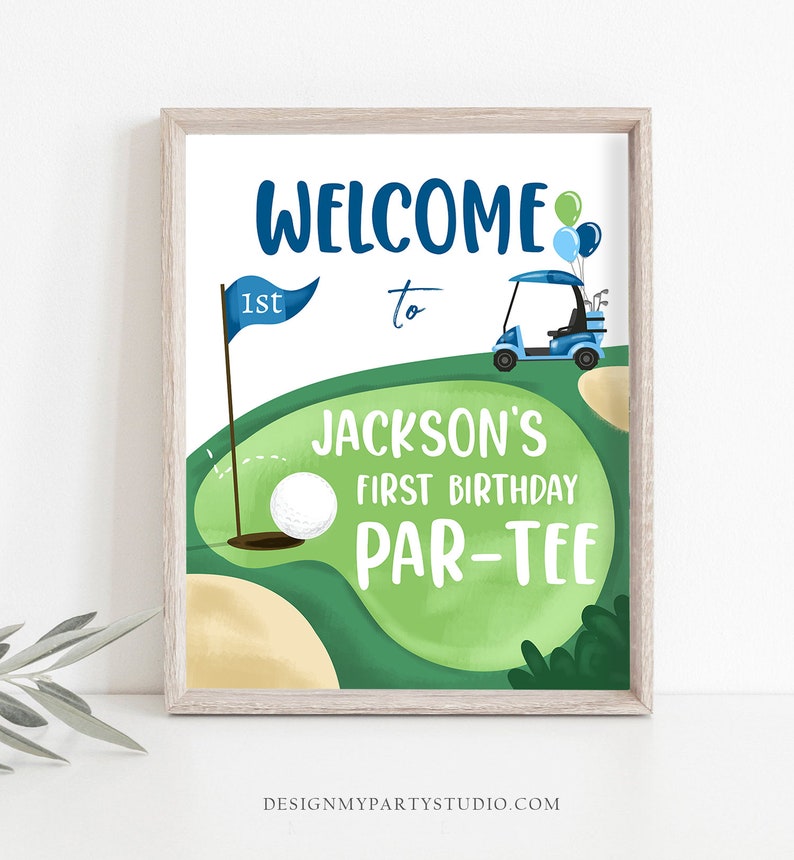 May include: A green and brown golf course with a blue golf cart, a golf ball, and a flag with the number "1st" on it. The text "Welcome to Jackson's First Birthday Par-Tee" is written on the sign.