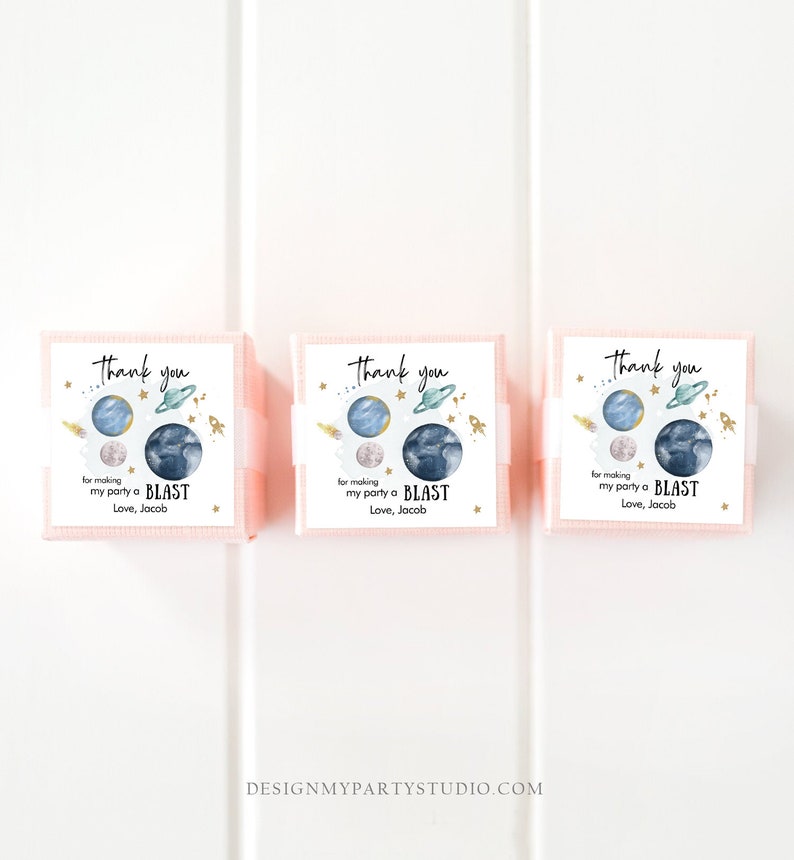 May include: Three pink favor boxes with thank you labels. The labels feature a watercolor illustration of planets and stars with gold accents. The text on the labels reads "Thank you for making my party a BLAST Love, Jacob".