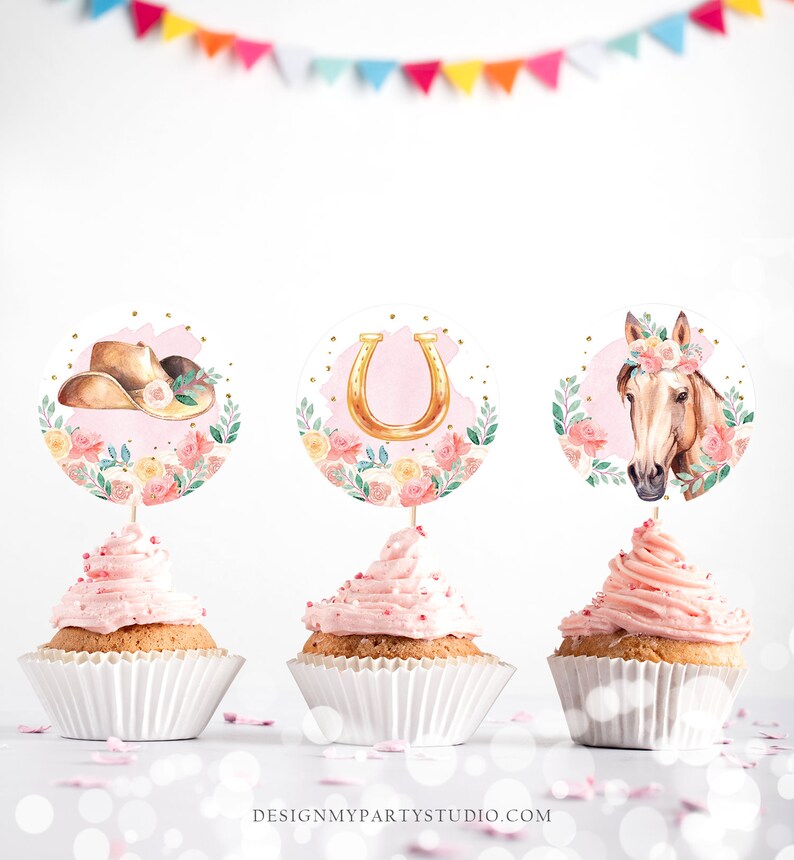 May include: Three pink cupcakes with white frosting and sprinkles. Each cupcake has a round topper with a pink floral design. The toppers feature a cowboy hat, a horseshoe, and a horse's head.