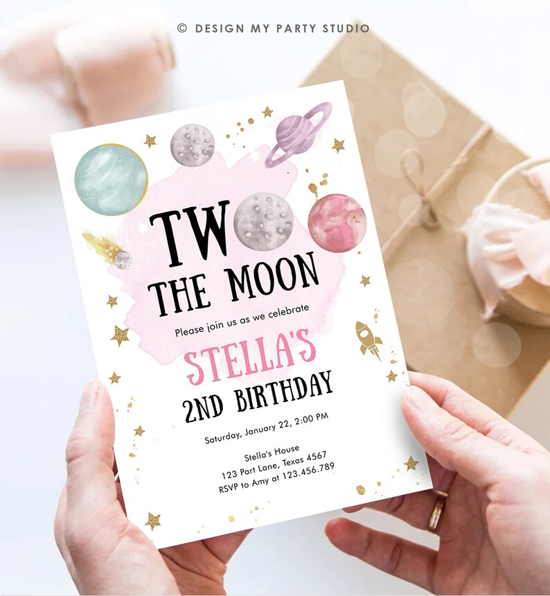 May include: A pink and white invitation with gold stars and planets. The text reads "Two the Moon, Please join us as we celebrate Stella's 2nd Birthday, Saturday, January 22, 2:00 PM, Stella's House, 123 Part Lane, Texas 4567, RSVP to Amy at 123.456.789".
