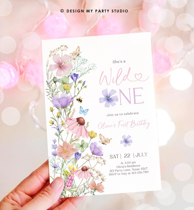 May include: A floral-themed first birthday invitation with a watercolor design featuring pink, purple, and yellow flowers, butterflies, and a bee. The text reads "She's a Wild One" and includes details for the party, including the date, time, location, and RSVP information.