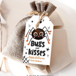 Pu&ograve; includere: Un'etichetta regalo rettangolare bianca legata con uno spago a un sacchetto di iuta. L'etichetta presenta un ragno disegnato con stivali arancioni, il testo Bugs and kisses e la scritta Happy Halloween from Madison.