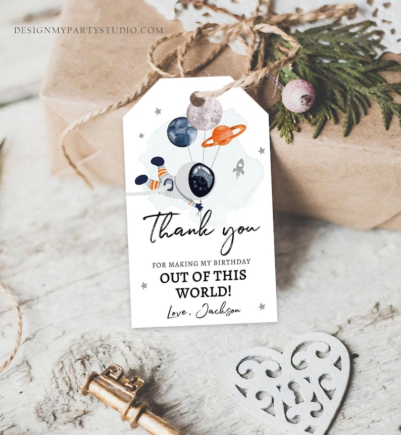 May include: A white thank you tag with an astronaut holding balloons shaped like planets. The text reads "Thank you for making my birthday out of this world! Love, Jackson".