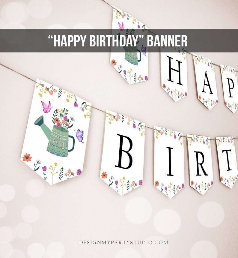 May include: A white banner with a floral design and the words "HAPPY BIRTHDAY" in black letters. The banner is strung with twine and has a watering can with flowers and butterflies on one end.