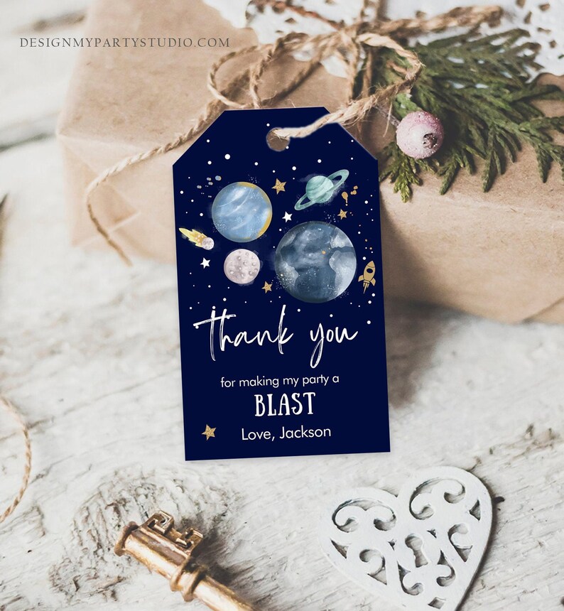 May include: Blue thank you tag with a space theme. It features planets, stars, and a rocket ship. The text reads "Thank you for making my party a BLAST. Love, Jackson."