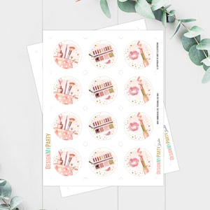 Puede incluir: Doce pegatinas redondas con un tema de maquillaje. Las pegatinas presentan im&aacute;genes de pinceles de maquillaje, paletas de sombras de ojos y l&aacute;piz labial. Las pegatinas est&aacute;n sobre un fondo blanco con detalles de purpurina dorada.