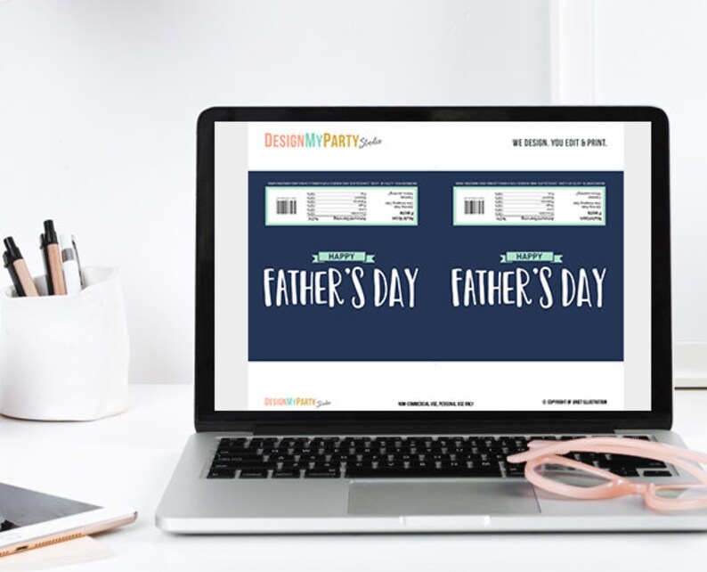 Pu&ograve; includere: Uno schermo di un portatile mostra un modello stampabile di incarto per barretta di cioccolato per la festa del pap&agrave;. Il design digitale blu scuro presenta il testo HAPPY FATHER'S DAY in bianco, un banner azzurro e una tabella nutrizionale.