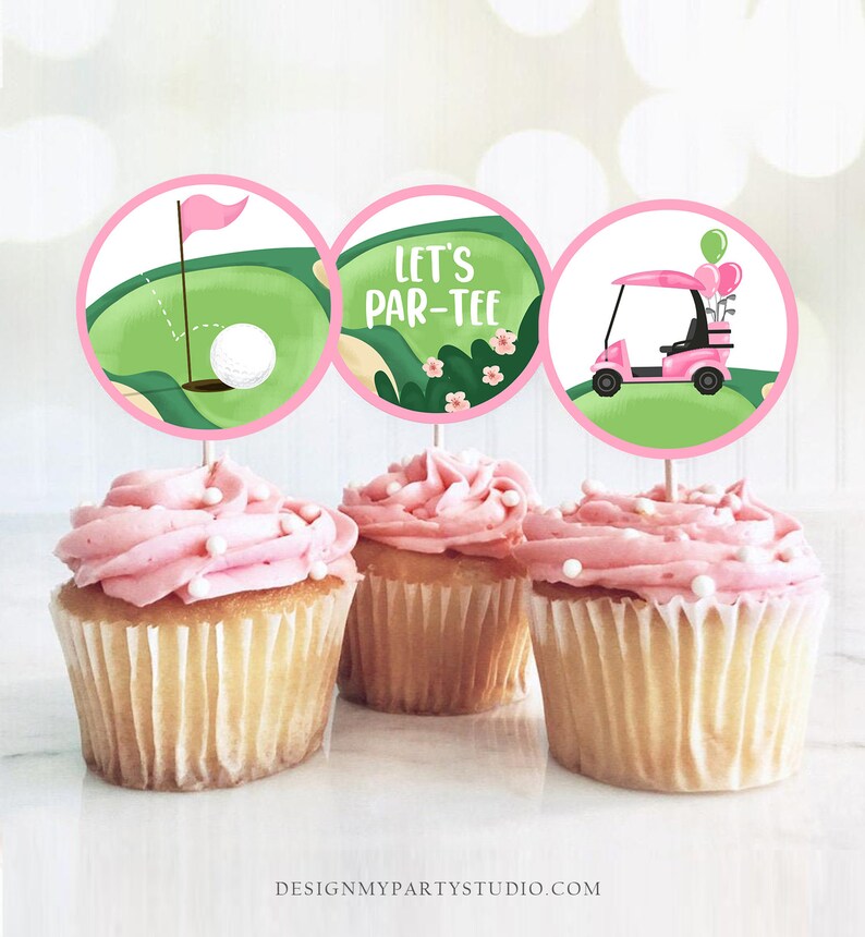 May include: Three pink and green cupcake toppers with golf-themed designs. One topper features a golf ball and flag on a green, One topper says "Let's Par-Tee", and the other topper features a pink golf cart with balloons.