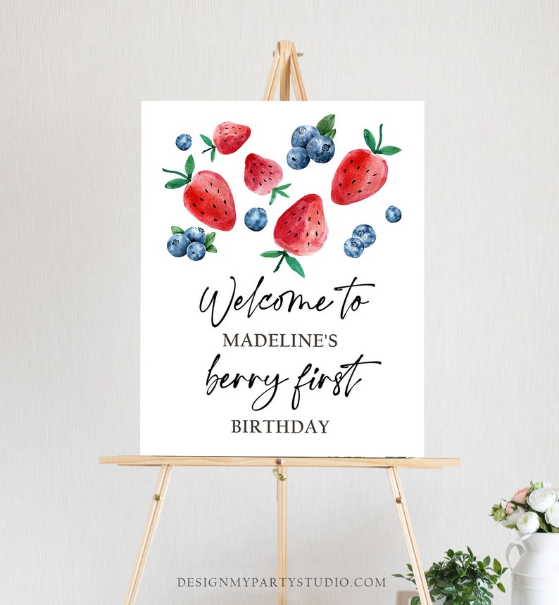 May include: Welcome to Madeline's Berry First Birthday sign with watercolor illustrations of strawberries and blueberries on a white background.